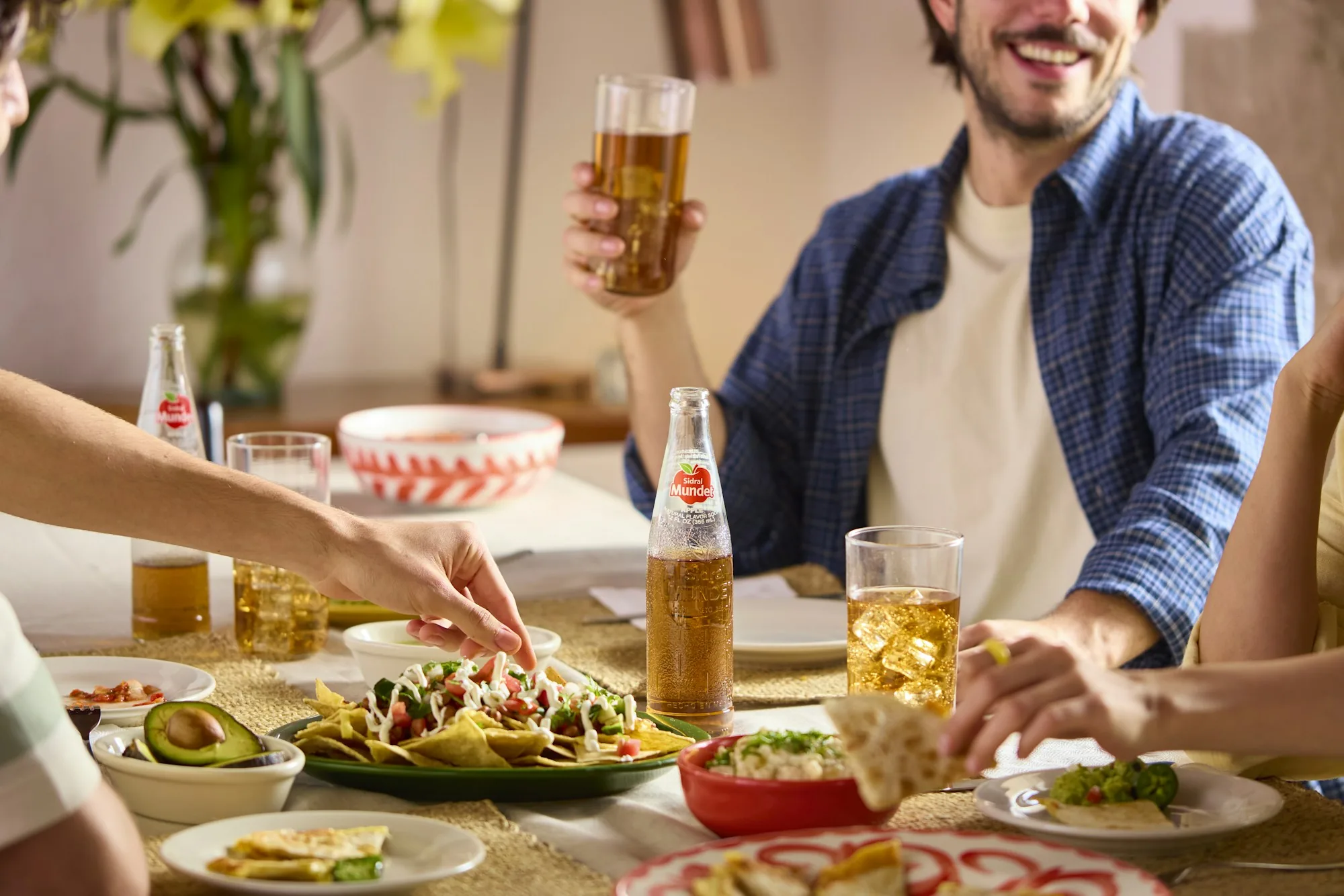 Friends sharing a meal around a timber table, reaching for plates